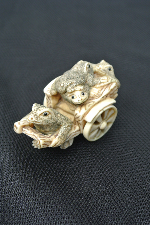 Japan School 19th century. A well-executed carved ivory netsuke in the form of four frogs over a