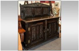 A Large Carved Oak Baronial Two Door Cupboard with a carved top crest, profusely to door & top with