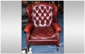 Reproduction Burgundy Button Backed Leather Armchair with wing sides, on scrolling arms. In the