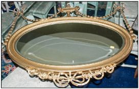 A Composition Gilded Regency Style Drawing Room Oval Shaped Mirror urn centre with applied swaggers