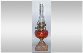 A Victorian Ruby Glass Font Oil Lamp On Cast Iron Floral Decorated Base, with a glass funnel. No