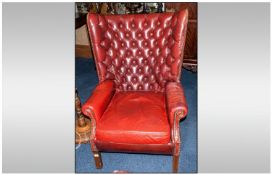 A Georgian Style Brown Leather Button Back Armchair with a bowed back, on scrolling arms, loose