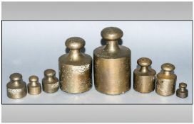 A Ser Of 8 Antique Brass Graduating Dump Weights. Largest measuring 5``. With carrying finials to