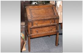 An Edwardian Two Drawer Oak Drop Down Front Bureau with fitted interior on square legs.