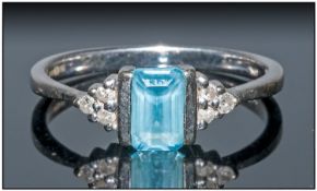 9ct White Gold Dress Ring Set with a central emerald cut blue topaz between 6 round brilliant cut
