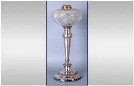 An Oil Lamp with a cut glass font supported on a silver plated candle stick type base. With a