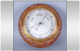 A Round Carved Oak Edwardian Wall Barometer with a brass rim and a steel dial. 7 inches in