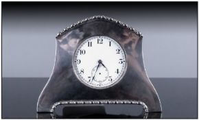 A Silver Cased And Shaped Small Table/Desk Clock, with piecrust borders and pocket watch size dial.