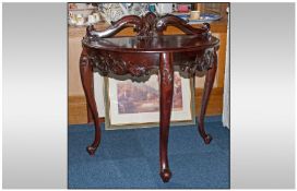 A Reproductions carved Mahogany Demi Lune Hall Table with a Shaped Carved top. Bevil & shaped