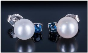 Pair Of Platinum Mounted Pearl Earrings, Single white pearl above a round cut blue Sapphire. Fully