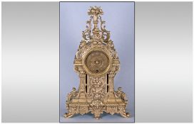 A French Style Cast Brass Mantel Clock with a Brass Round Dial In a Fancy Roccocco Style Case.