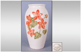 Moorcroft Contemporary Lily Pattern Vase, light terracotta flowers and green leaves on a plain