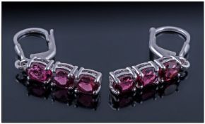 Rhodolite Garnet Three Stone Drop Earrings, each earring having three oval cut stones of the rich,