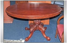 A Victorian Mahogany Oval Topped Table. On 4 carved cabriole legs with a carved central column.