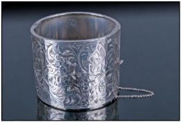 A Large And Impressive Silver Hinged Bangle, with safety chain and chased decoration. Hallmark