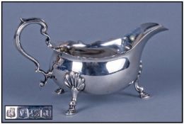 A Silver Sauce Boat, with scroll handle, wave borders and raised on four hoof feet. Hallmark