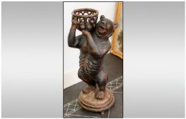 A Large Carved Wood Black Forest Type Bear Plant Stand depicting a bear carrying a basket, well