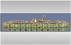 Peridot Tennis Bracelet, a row of oval cut, faceted brilliant green peridots, totalling 12.75cts,