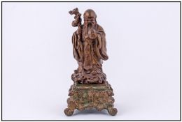 A Chinese Cast Bronze Figure of a Lohan, holding a staff and peach in each hand. Fitted on an