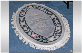 A Chinese oval Shaped Floral Embossed Carpet with a bluey grey ground with coloured roses. Approx 70