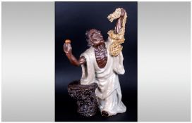 A Late 19th Century Stoneware And glazed Oriental Figure of a man dressed in robes holding a