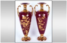 Pair of Tall Magenta and Gilt Two Handled Vases, the elongated ovoid bodies with gilt floral sprays