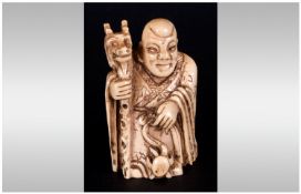 Japanese Signed & Carved Ivory Netsuke Circa 1900, in the form of a cloaked priest/man holding a