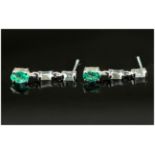 Pair of Emerald Drop Earrings, an oval cut emerald suspended below two baguette cut white topaz in