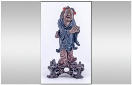 A Hand Carved Lacquered Wooden Japanese Figure Of A Deity, standing on a scrolling rocky base,