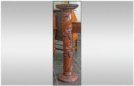 A Carved Mahogany Column Pedestal with trailing vines, carved to the centre. With a carved round