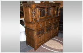A Priory Type Oak Court Cupboard, with a leaded glass top, flanked by carved side panels,