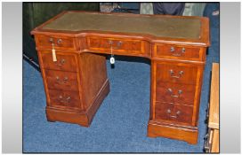 A Reproduction Yew Wood Knee Hole Writing Desk with shaped front & green leather top. A bank of 4