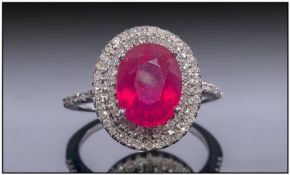 14ct White Gold Diamond Ring, Set With Central Oval Cut Ruby Surrounded By Two Rows Of Diamonds.