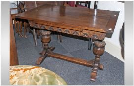 A Carved Oak Draw Leaf Dining Table In The Jacobean Style, with carved bulbous supports on a crossed