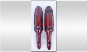 A Pair of African Hardwood Carved Elongated Wall Hanging Masks of a male and female. 22 inches in