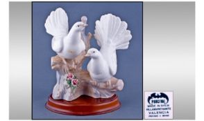 Porceval Lladro Style Pair Of Doves. Raised on an oval wooden stepped plinth. Height 9.25 inches.