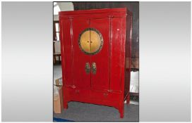 A Chinese Red Lacquered Marriage Cabinet, with large central boss to the doors, pair of enamel