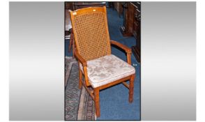 A Wicker Back Teak Arm Chair, with bamboo simulated legs, on overstuffed upholstered seats.
