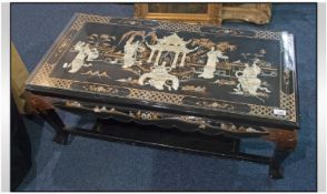 A Chinese Lacquered Coffee Table, with glass top. The inverted top embossed with Chinese figures in