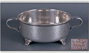 An Arts And Crafts Twin Handled Silver Plated Bowl. The planished bowl on four bracket feet. Maker