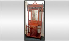 A Carved Mahogany Hall Stand with a cupboard centre above a drawer, spindles to the side for