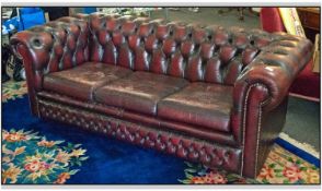 A Three Seater Burgandy Coloured Leather Button Backed Club Settee. Worn condition with 3 loose