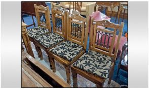 A Set Of Four Teak Dining Chairs, with solid seats and loose fabric cushions, on turned legs with