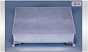 A Good Quality Silver Table Cigarette Box, with engine turned lid. Raised on 4 splayed feet.