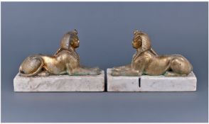 A Pair Of Bronze/Brass Reclining Antique Models Of Sphynx`s on white marble bases. 10.5`` in