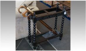 A 1920`s Carved Oak Stick Stand on rope twist legs, with a lift in tin shelf to the base, with 6