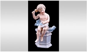 A Small Dresden Type Figure Of A Putti, sitting on a pedestal chiselling at a piece of marble. Late
