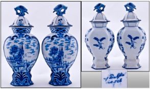 A Pair of Delft Blue Pottery Vases with canal scene decoration with parrot bird finials to the