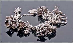 Silver Charm Bracelet Loaded With 11 Charms, Complete With Padlock And Chain Fastener.