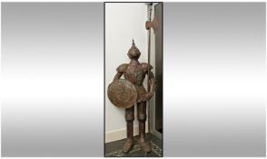 A Full Size Decorative Metal Suit Of Armour, in the 16th century style, holding a round shield and